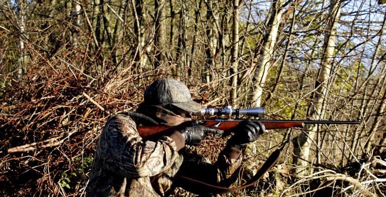 Man hunting in woods with bolt action